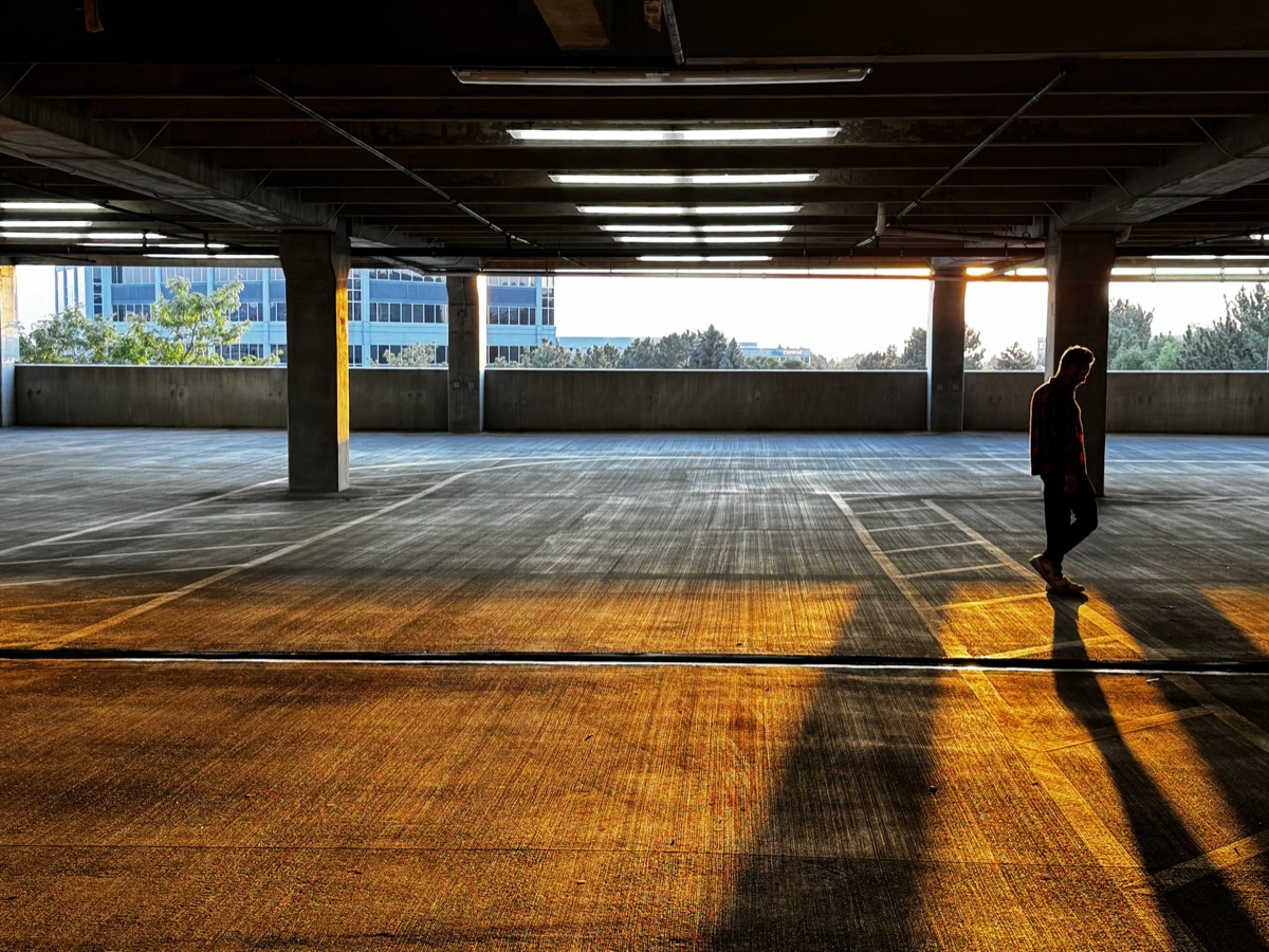 Figure crossing a parking structure in golden light